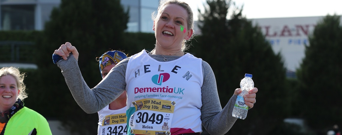 Helen Green smiling and raising her arms in celebration after completing a running race