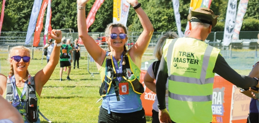 A runner holds her hands high in celebration at she crosses the finish line at a countryside-race
