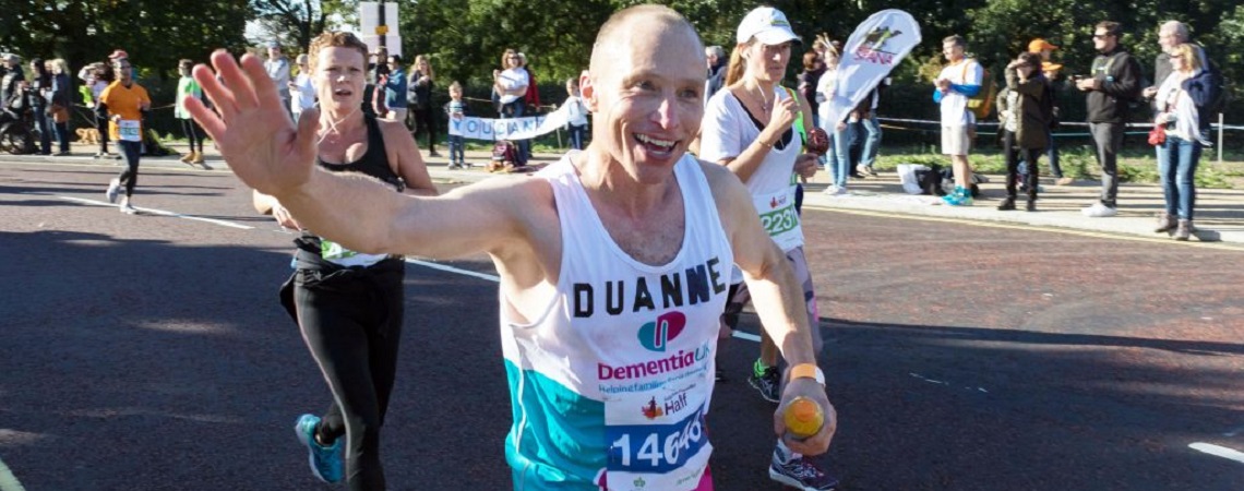 A runner waves as he runs a marathon in aid of Dementia UK