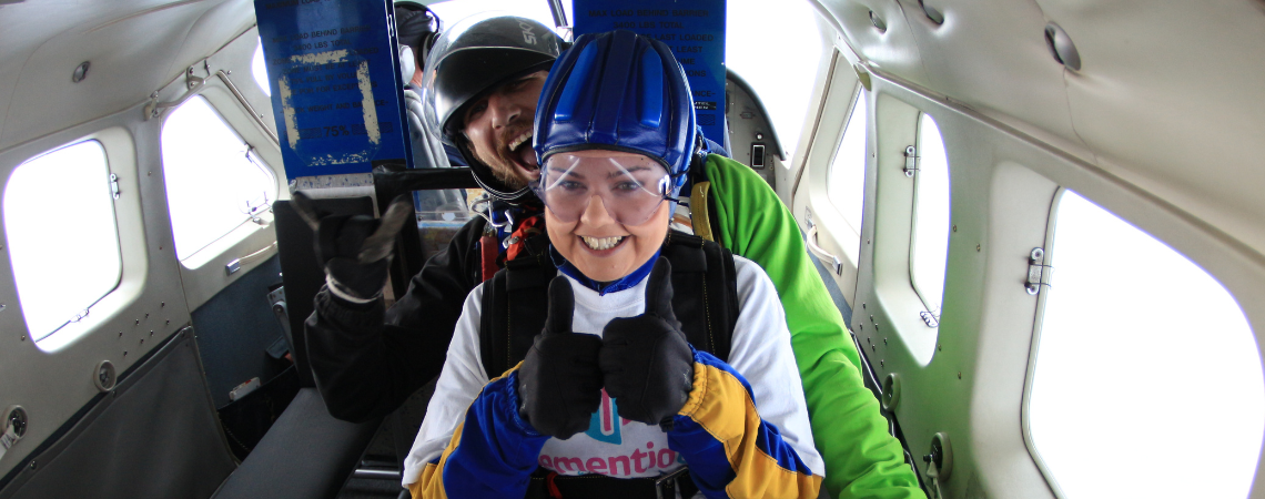 A woman prepares to skydive from a plane interior.