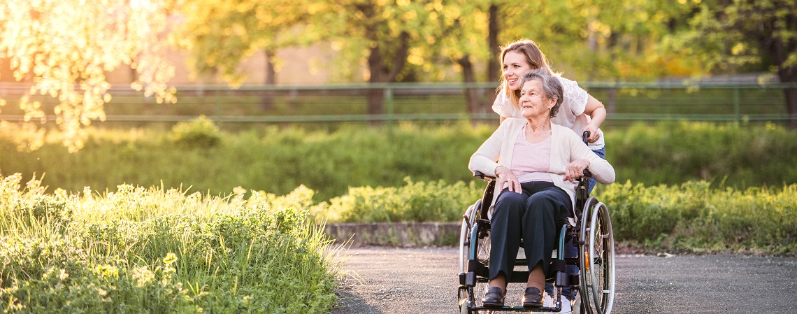 Lady in a wheelchair and person accompanying her enjoying the sunshine outside