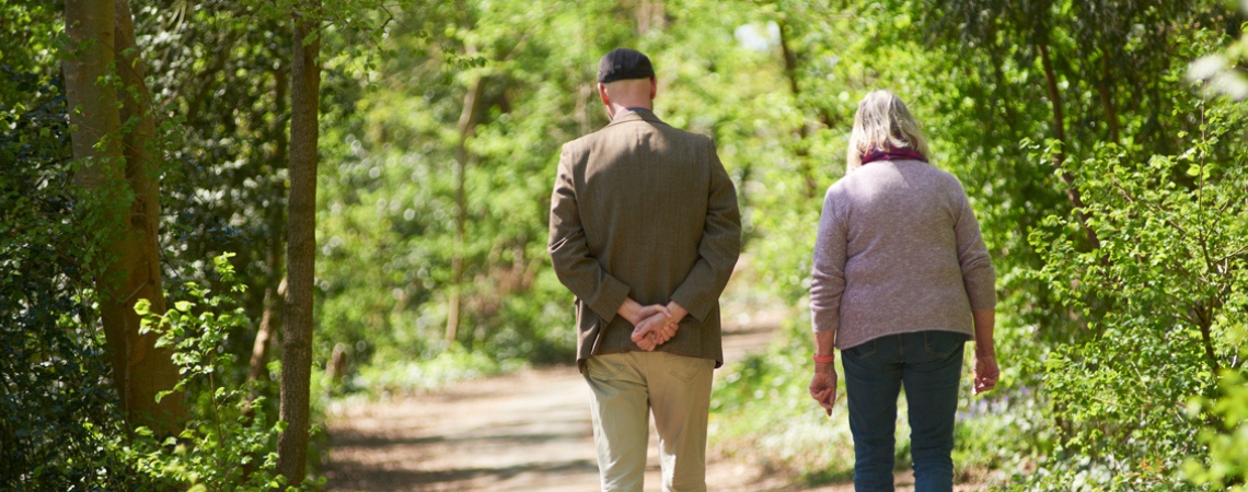 An elderly couple walk in the countryside