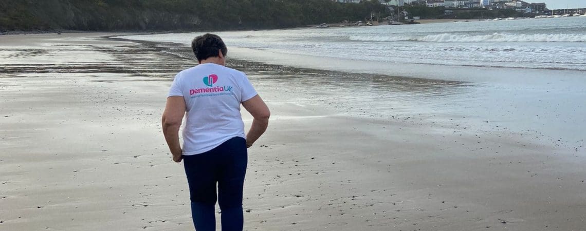 A man on a beach at dusk wearing a Dementia UK T shirt.