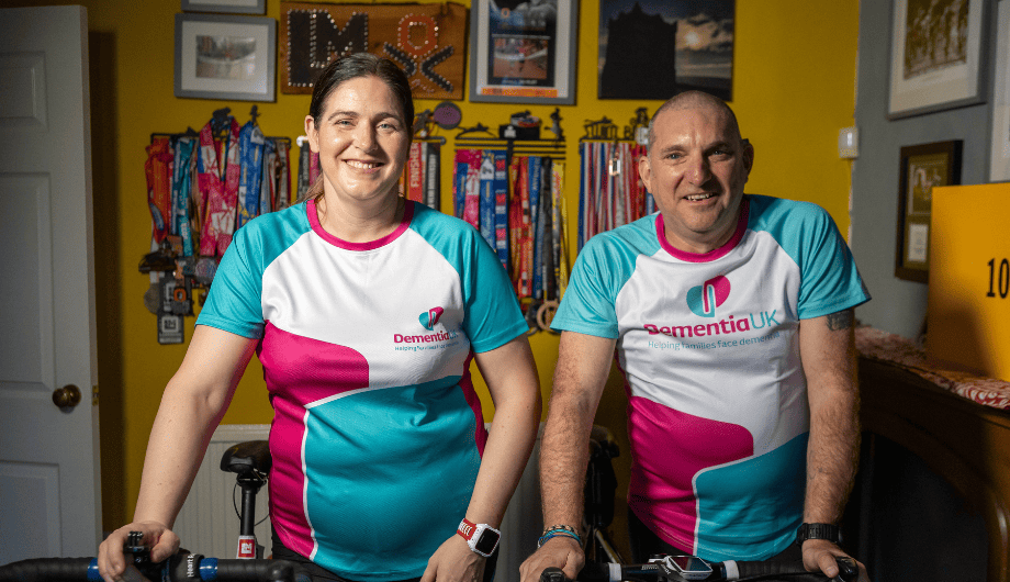 Christine (on left) and Andy (and right) wearing Dementia UK tops and posing next to bikes