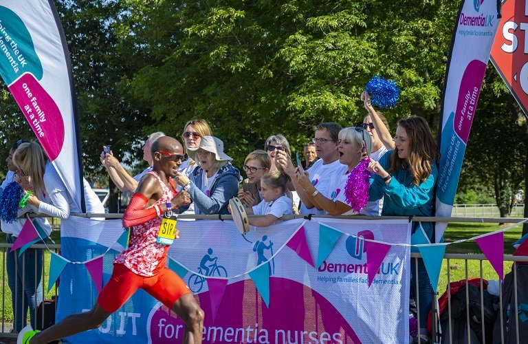 A group of people watching an organised race clapping and cheering on Dementia UK runners