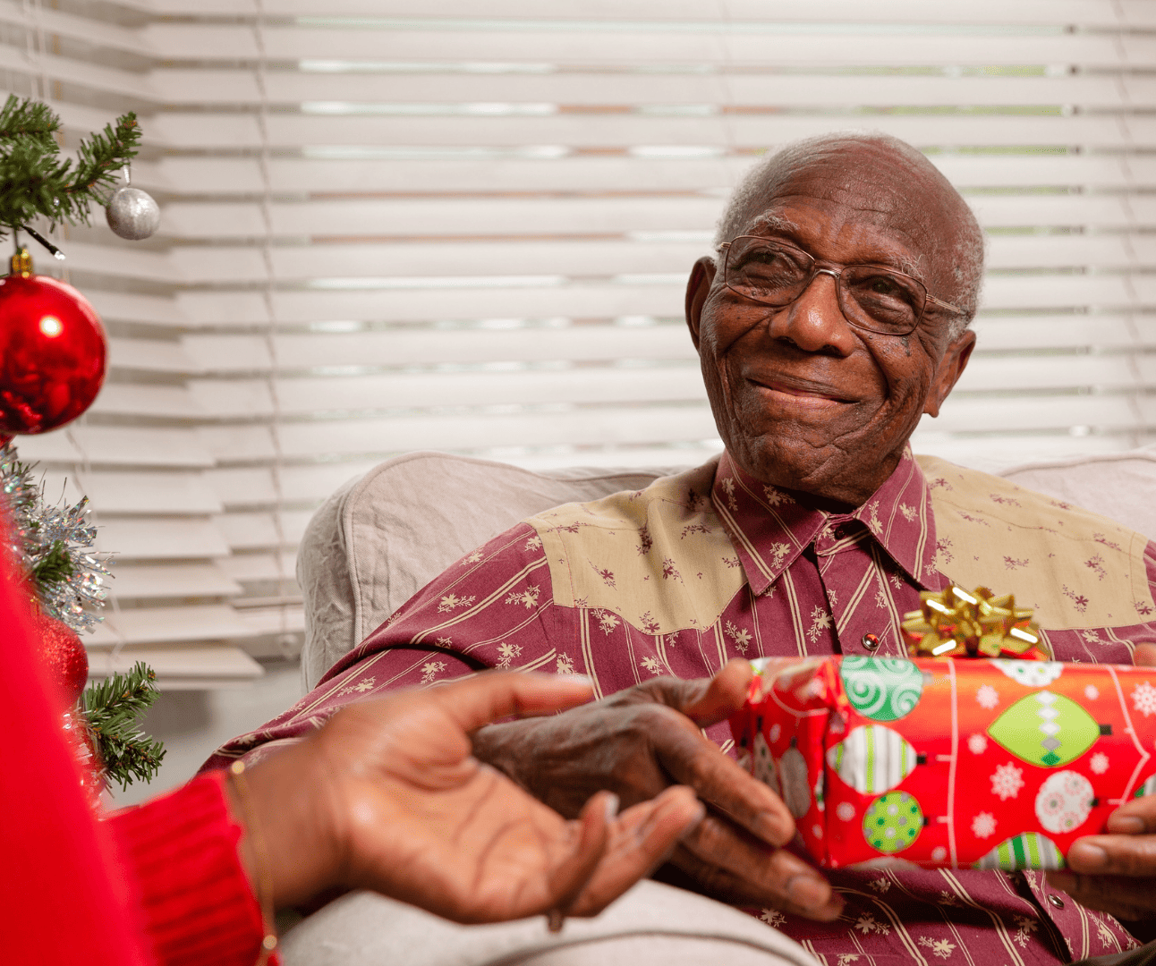 Man sitting on a sofa receiving a Christmas present