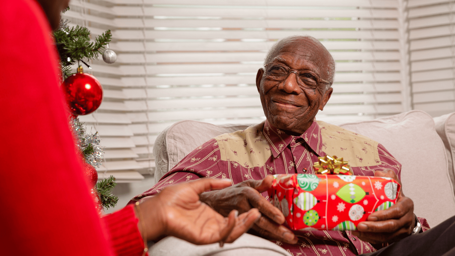 Man sitting on a sofa receiving a Christmas present