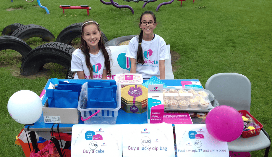Two girls fundraising outside their school for Dementia UK