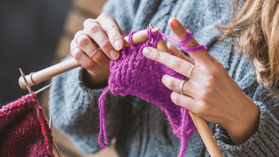close up of someone's hands while they knit