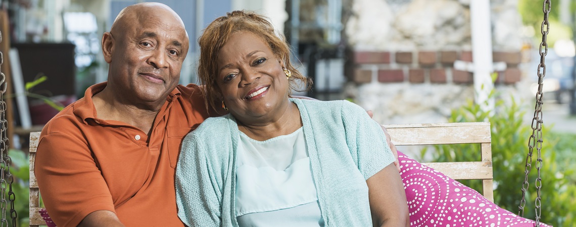 Senior black couple sitting on porch swing holding hands
