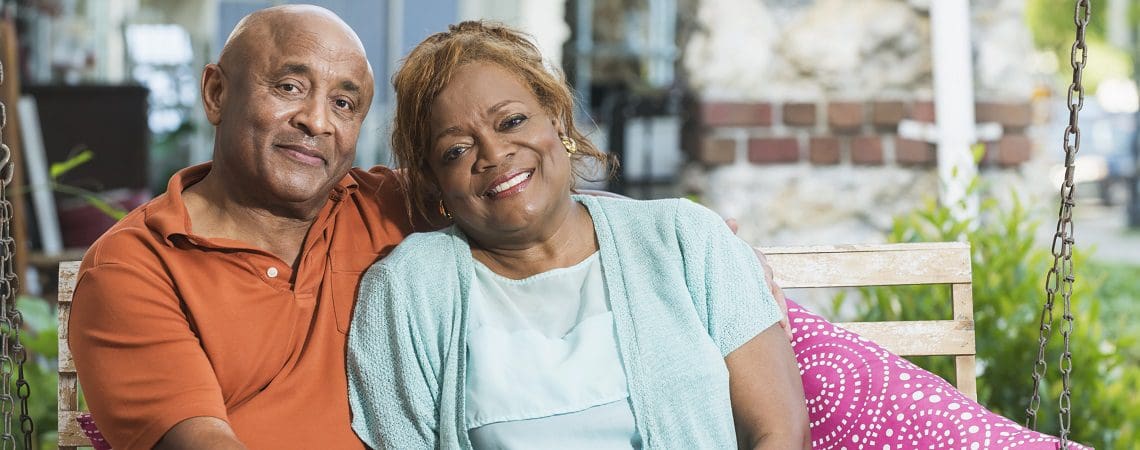 Senior black couple sitting on porch swing holding hands