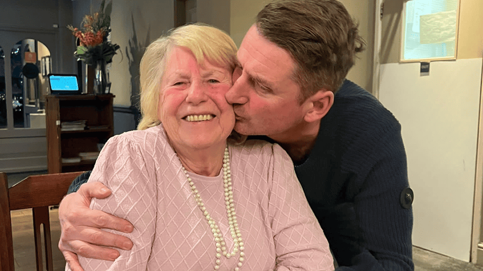 Admiral Nurse Phil kisses his mother Joan on the cheek as she smiles.