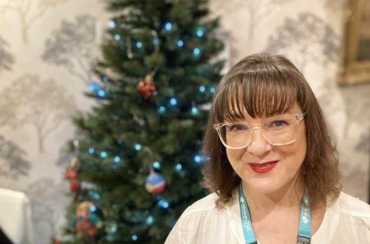 Admiral Nurse sitting next to a Christmas tree