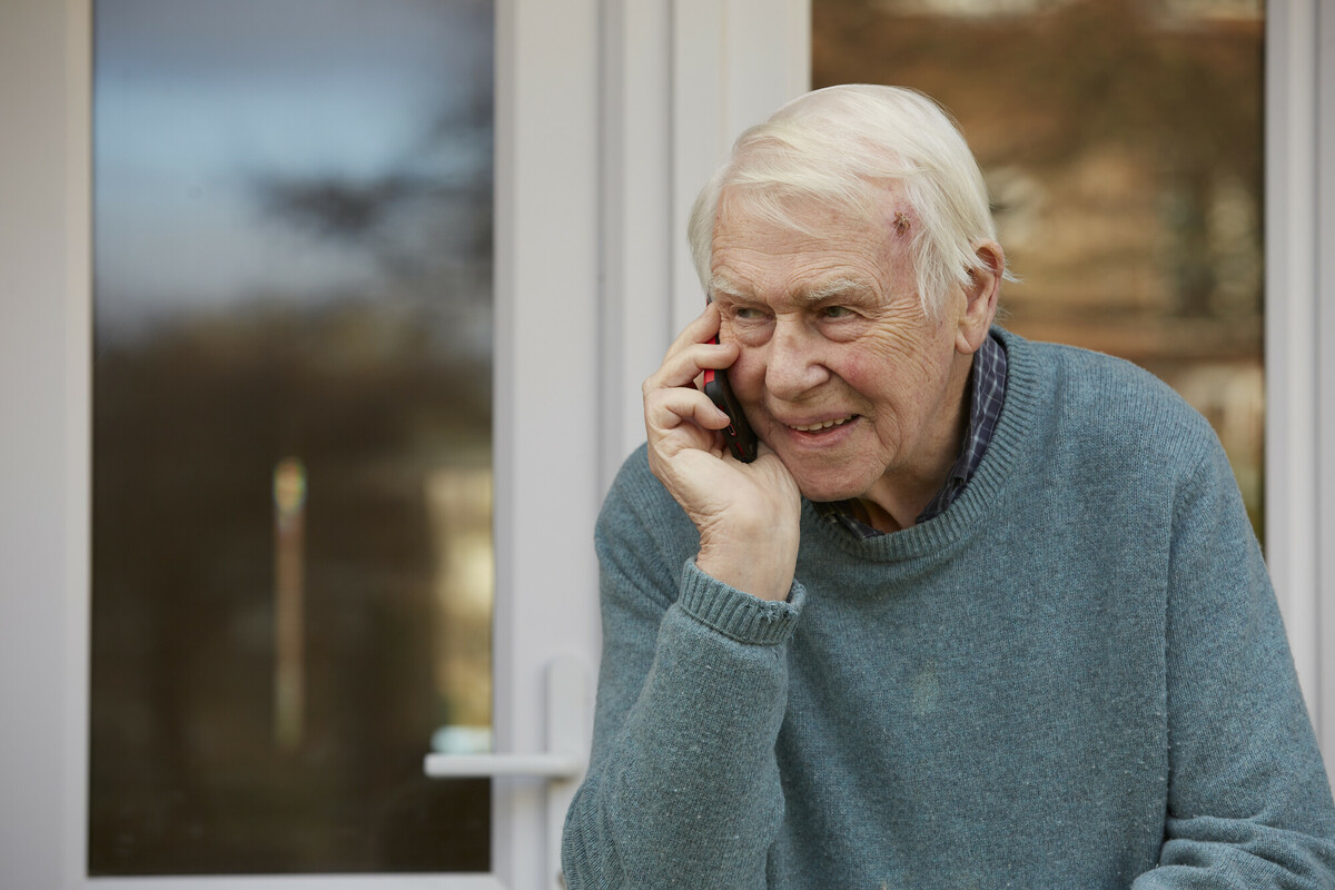 A man calls the Helpline. The carer/person with dementia is posed by an agency model on a city location shoot in London. This photo was taken in November 2022.