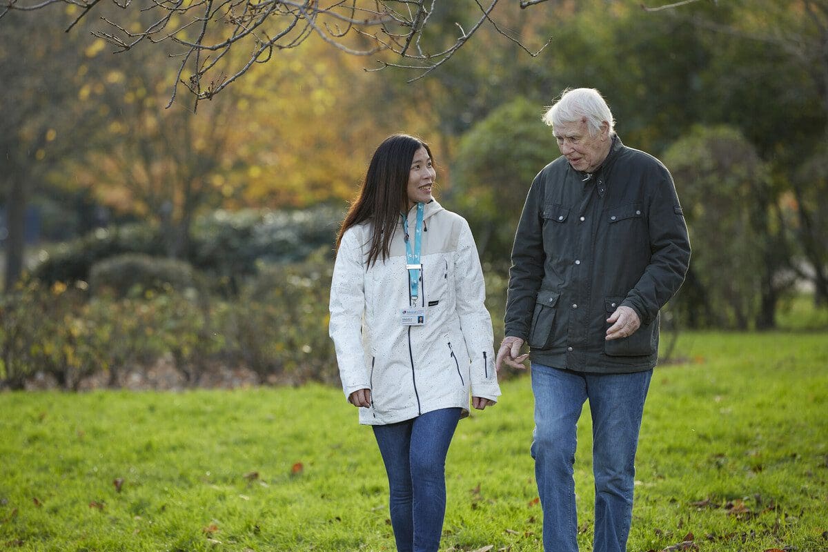 Emily, Dementia UK Admiral Nurse goes for a walk outside with a carer (agency model). Taken on a location shoot in London for the photo library in November 2022.