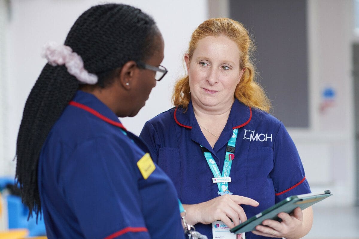 Admiral Nurses, Roxanne and Judy working in a clinical setting and looking at the Dementia UK website on a computer tablet.