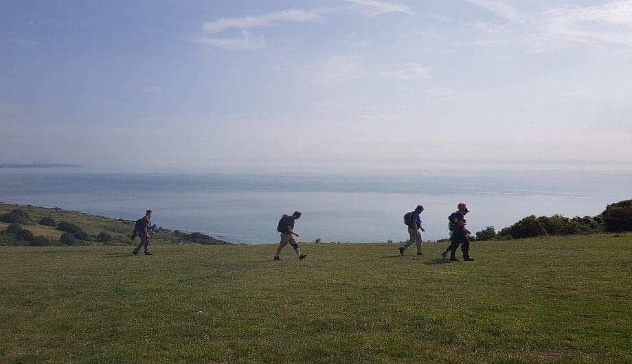 four people walking on a cliff with coastal views