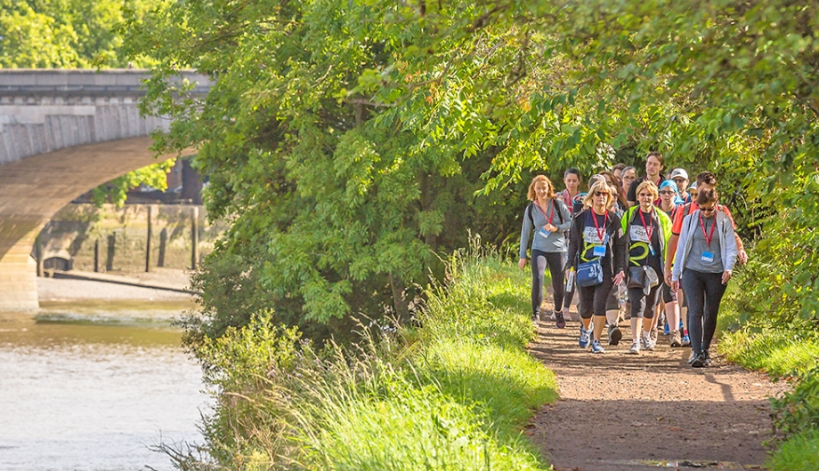group of people walking alongside the Thames canals with a bridge nearby