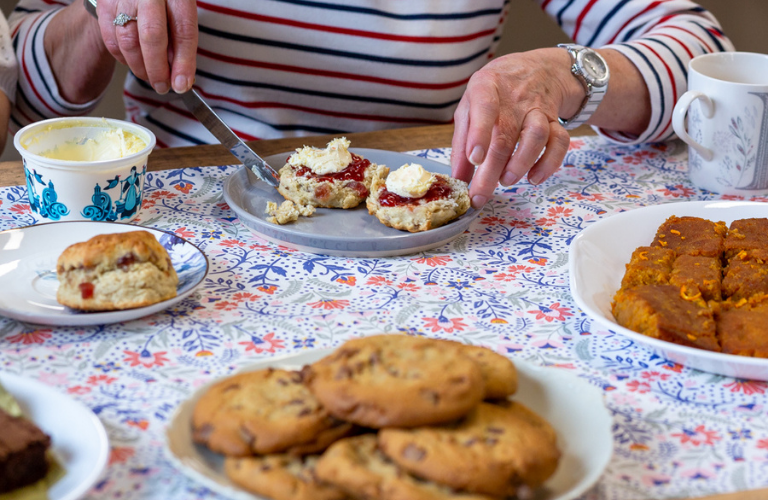 Jam and cream being spread onto a scone
