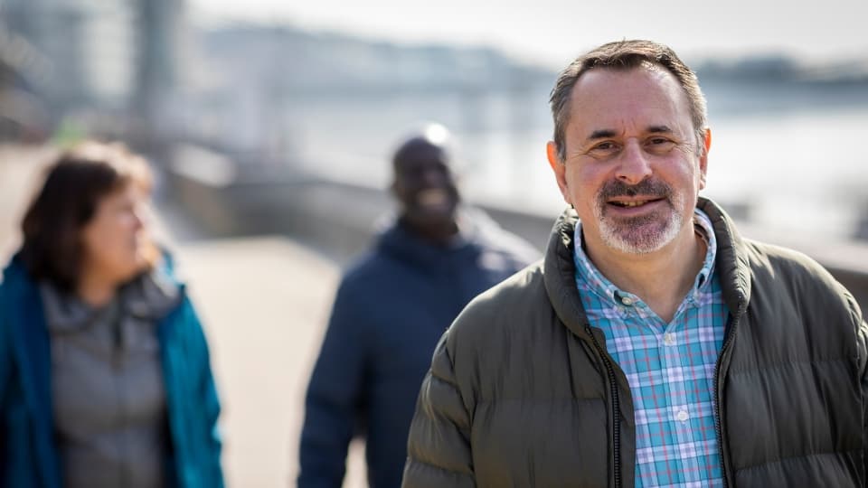 Middle aged man walking down a path near a river