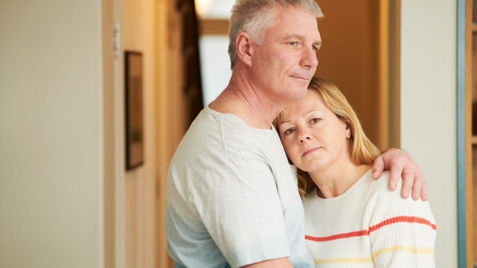 middle aged couple embrace. The wife looks concerned.